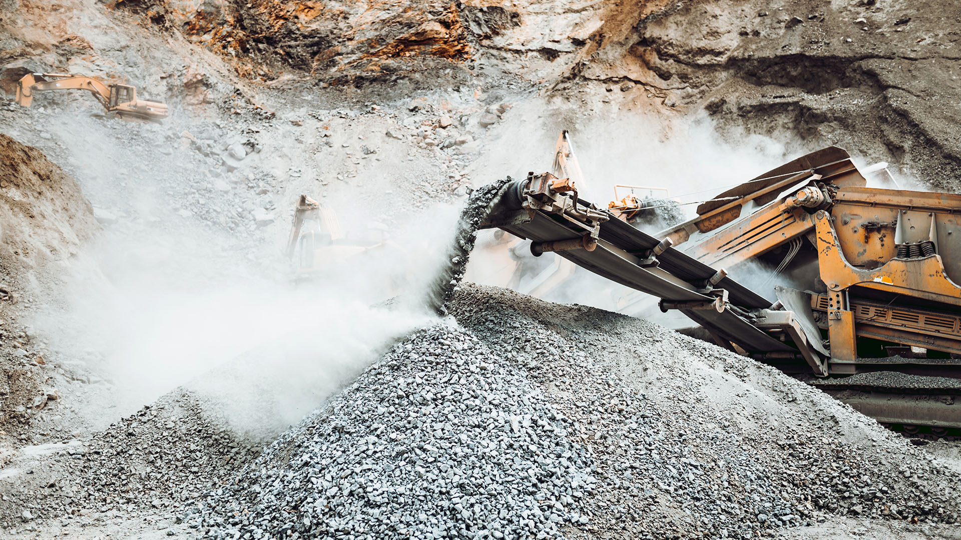 Industrial stone breaker rock crusher processing granite rocks at a quarry.